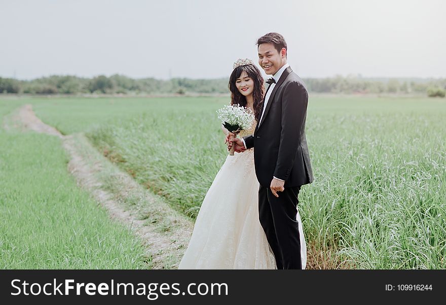 Man and Woman Wearing Wedding Dress and Suit in Between of Rice Fields