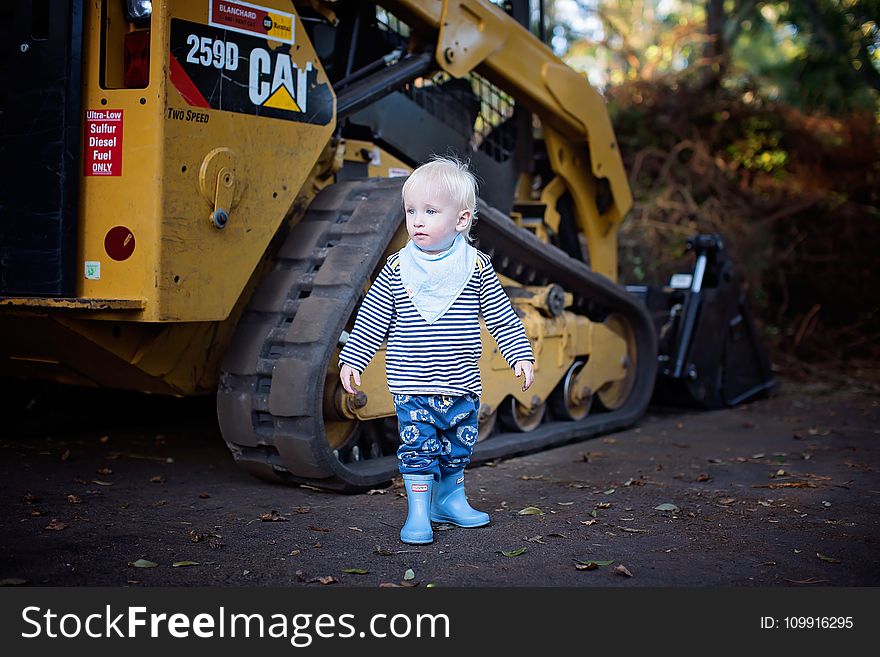 Baby Standing Near the CAT Skid Loader