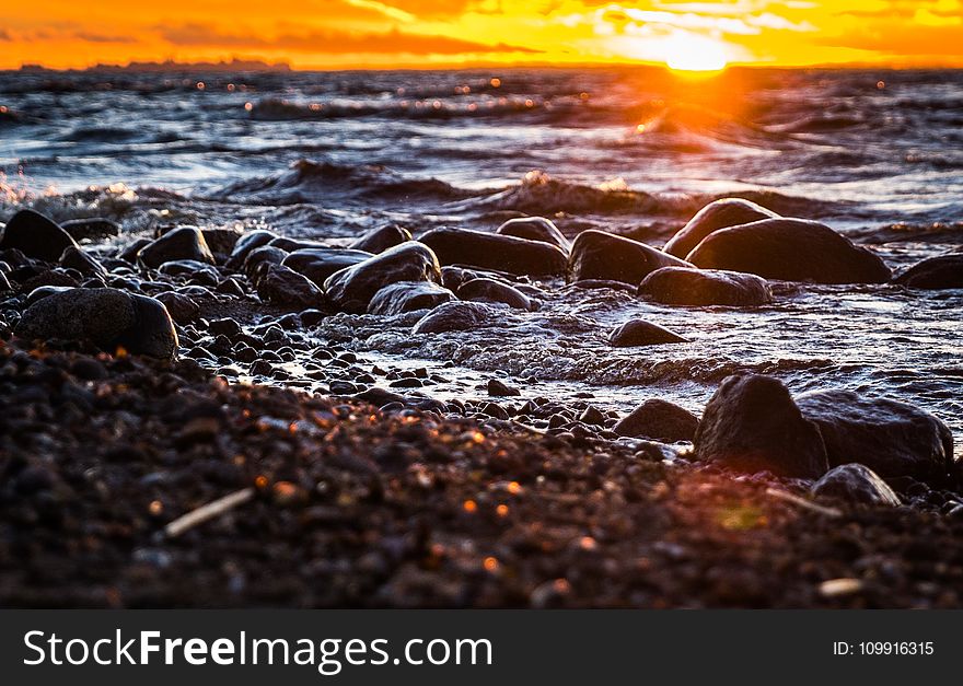 Stones Surrounded by Body of Water during Sunset