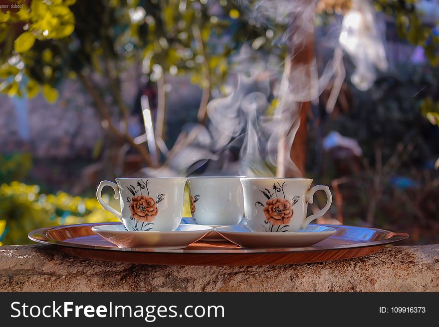 Shallow Focus Photo of Three White-brown-and-black Ceramic Floral Mugs on Saucers