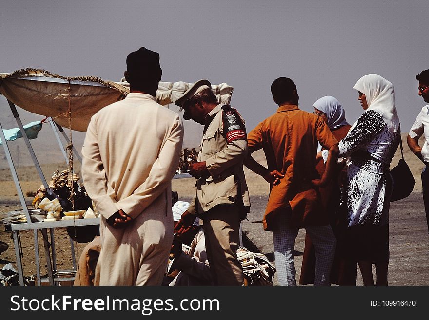 Group of People on Desert Beside Brown Tent
