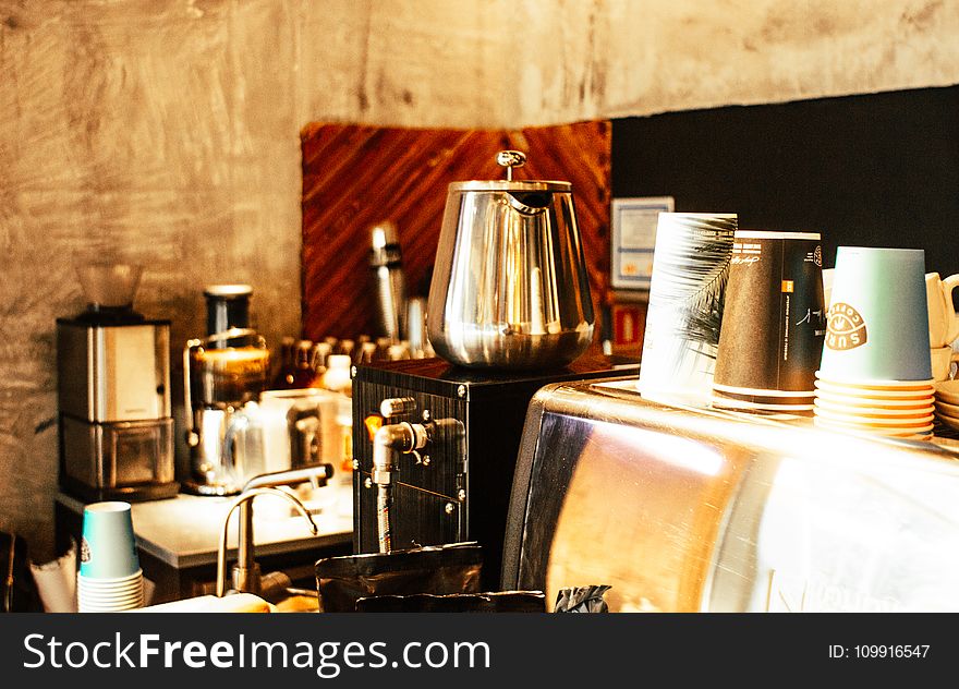 Stainless Steel Coffee Pot and Disposable Cups on Top of Counter