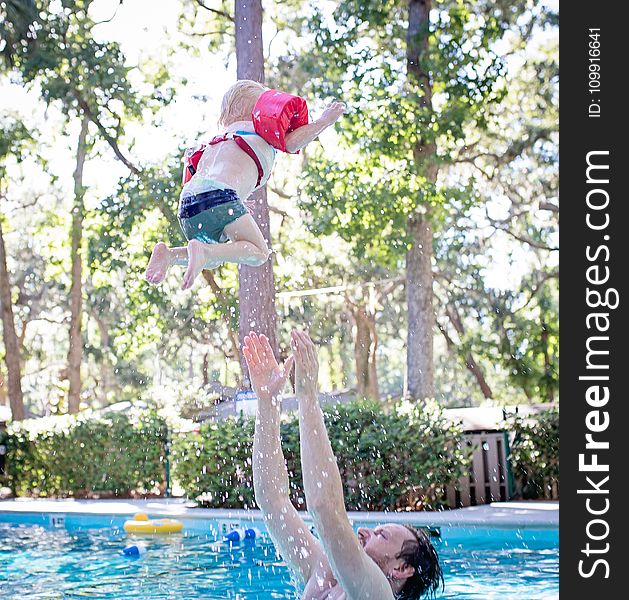 Photography Of Man On Swimming Pool Tossing Toddler Above Pool