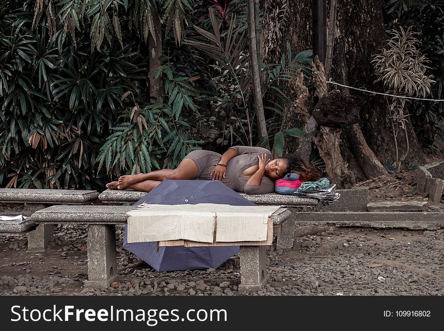 Woman in Gray Dress Lying on Bench