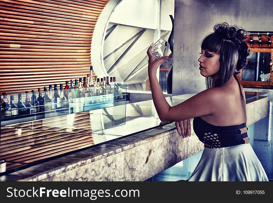 Woman in Black and Gray Backless Dress Sitting in Bar Desk