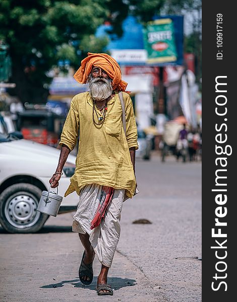 Man Walking On Street Carrying Metal Bucket