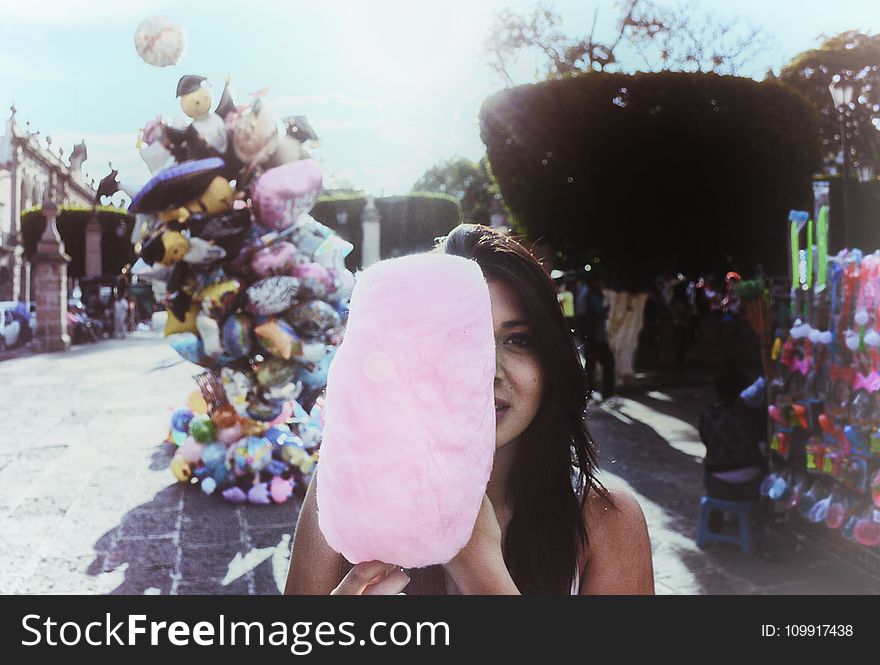 Woman Holding Cotton Candy With Balloons in Background