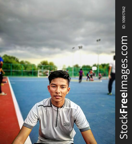 Tilt Lens Photography of Man Sitting Near Soccer Field during Cloudy Day