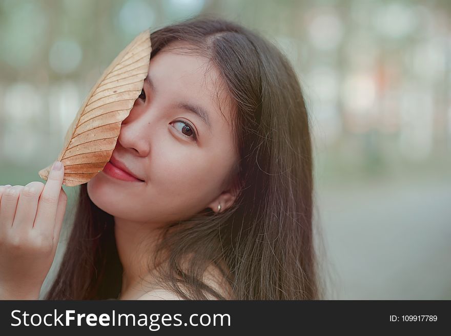 Photo of a Woman Holding a Dry Leaf