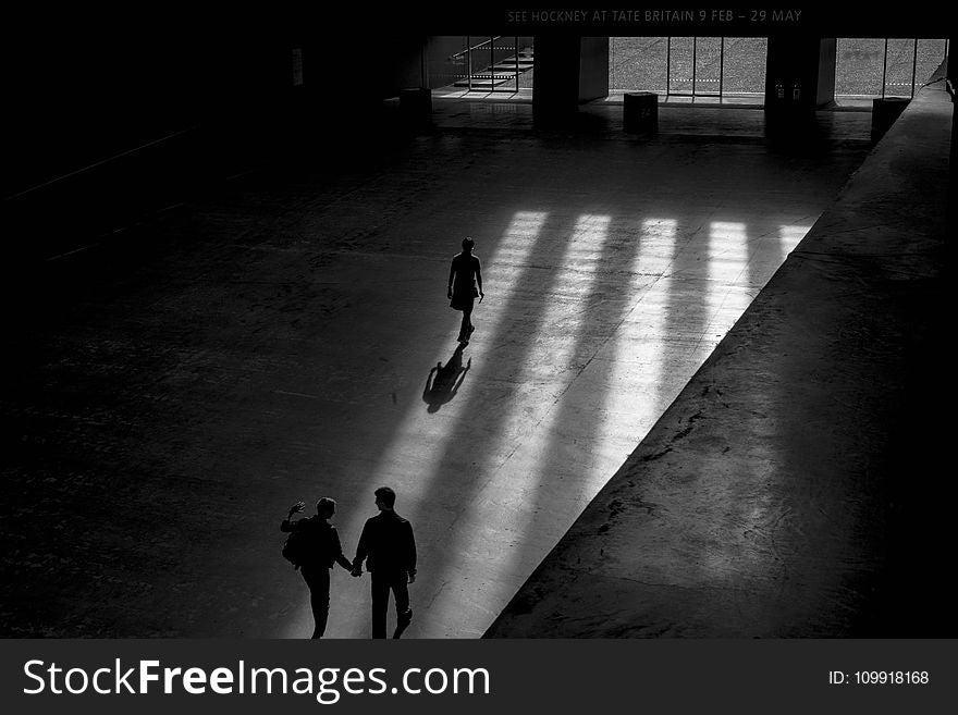 Grayscale Photo Of Three Men Walking Inside Building