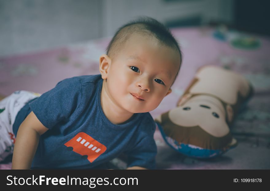 Close-Up Photography of Baby Lying on the Bed Near Bolster Pillow