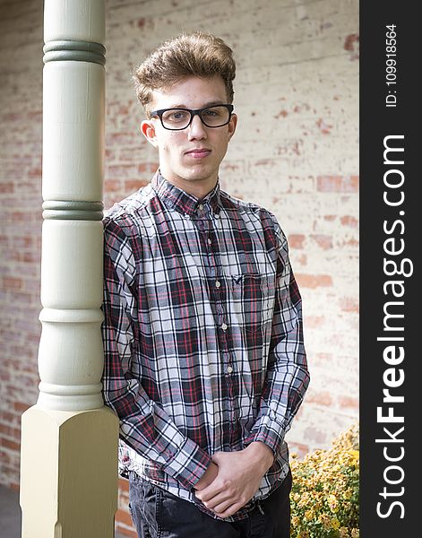 Man in Red Black and White Plaid-printed Dress Shirt Wearing Wayfarer Eyeglasses Leaning on White Wooden Post