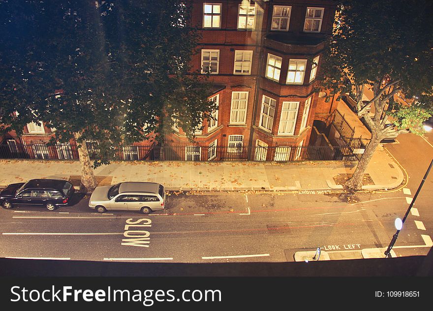 Two Cars Parked Near Brown Concrete Building During Nighttime