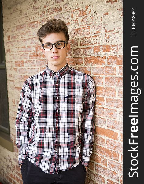 Man In Red And White Plaid Dress Shirt And Black Bottoms With Black Frame Eyeglasses