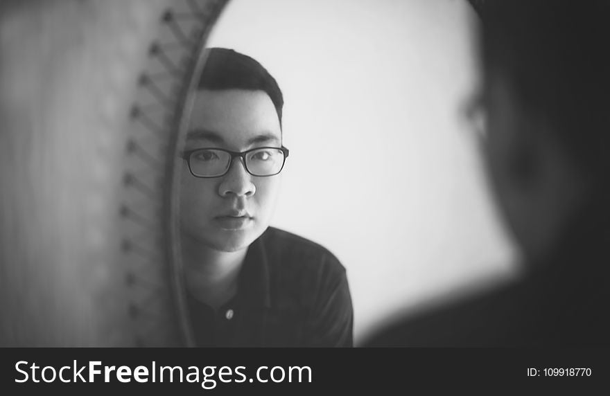 Monochrome Photography of a Man Looking In front of Mirror