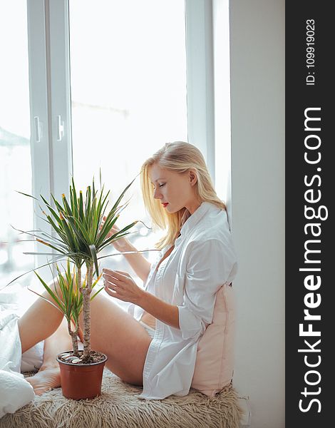 Woman Wearing White Long-sleeved Shirt Sitting Beside Green Plant