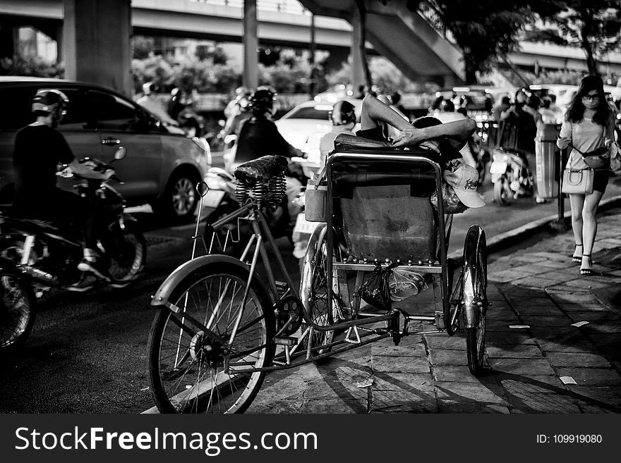 Greyscale Photo of Man Sitting On Sidecar oF Bicycle