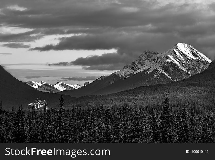 Grayscale Photography Of Snow Covered Mountain Under Cloudy Sky