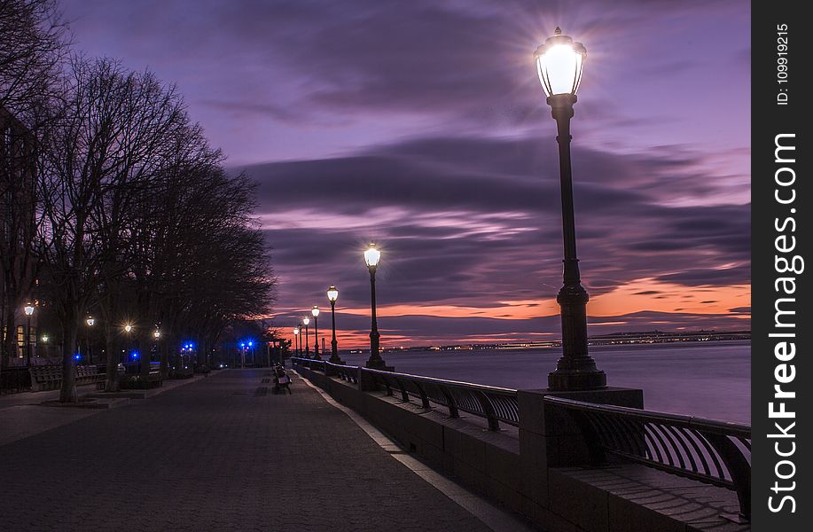 Photography Of Turned On Street Lamps Beside Bay During Night Time