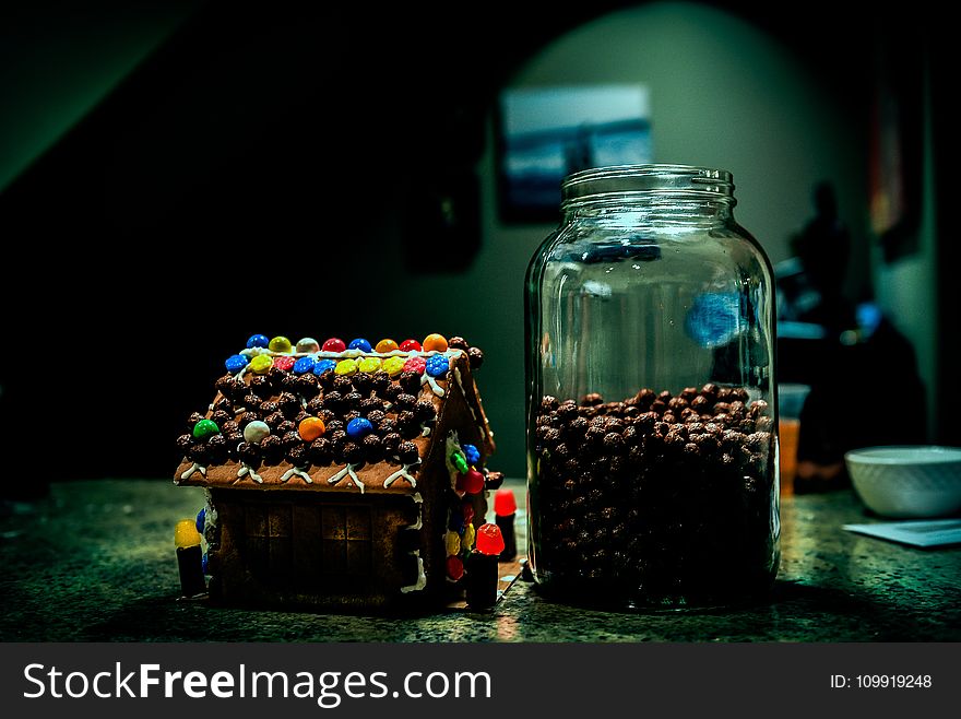 Gingerbread House Near Clear Glass Jar Filled With Candies