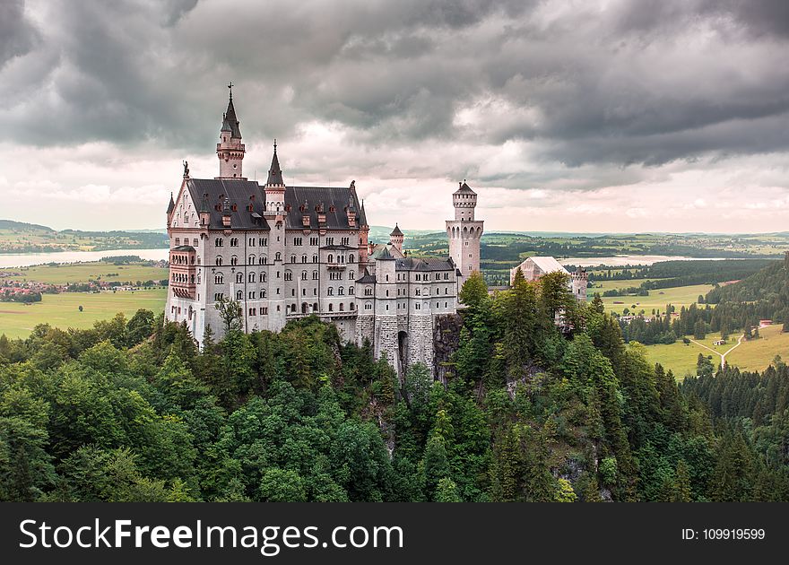 Aerial Photo Of White Castle With Green Leafed Tree Under White Cloudy Sky