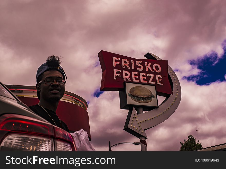 Man In Baseball Cap Near Frisko Freeze Signage