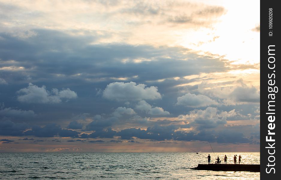 Silhouette Photo of People Standing on Dock Near Sea