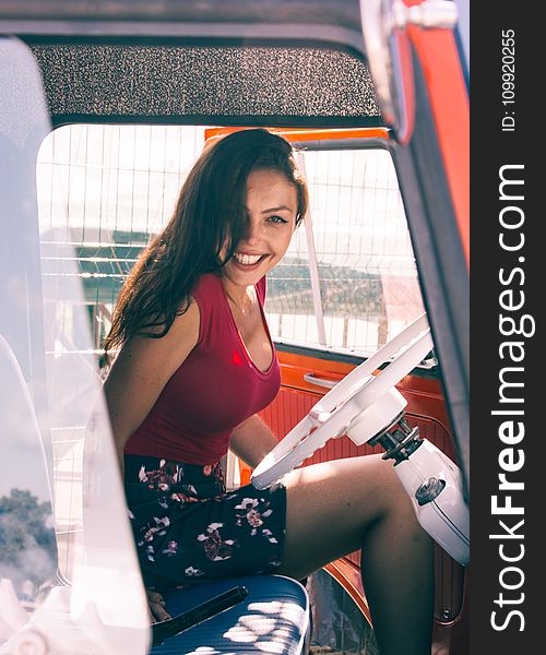 Woman In Red Shirt Sitting On Vehicle Seat At Daytime