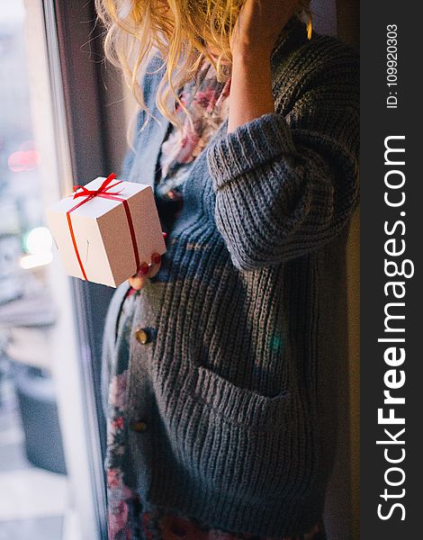 Woman Wearing Blue Knit Cardigan Holding Gift Box Inside Room