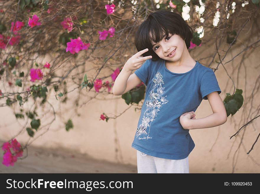 Girl In Blue Crew-neck T-shirt Next To Pink Petaled Flower
