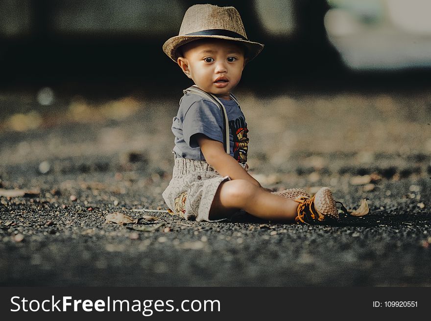 Child In Grey Shorts Sitting On Road