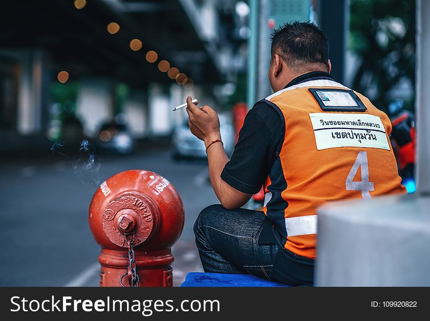 Man Wearing Orange And Black Polo Shirt Holding Cigarette