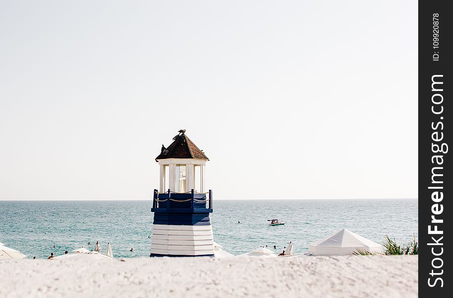 Photo Of Blue And White Painted Lighthouse Near The Beach