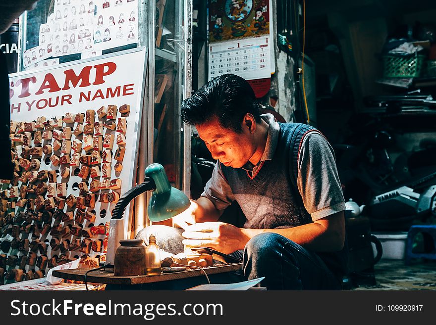 Man Holding Handheld Tool on Desk With Lamp