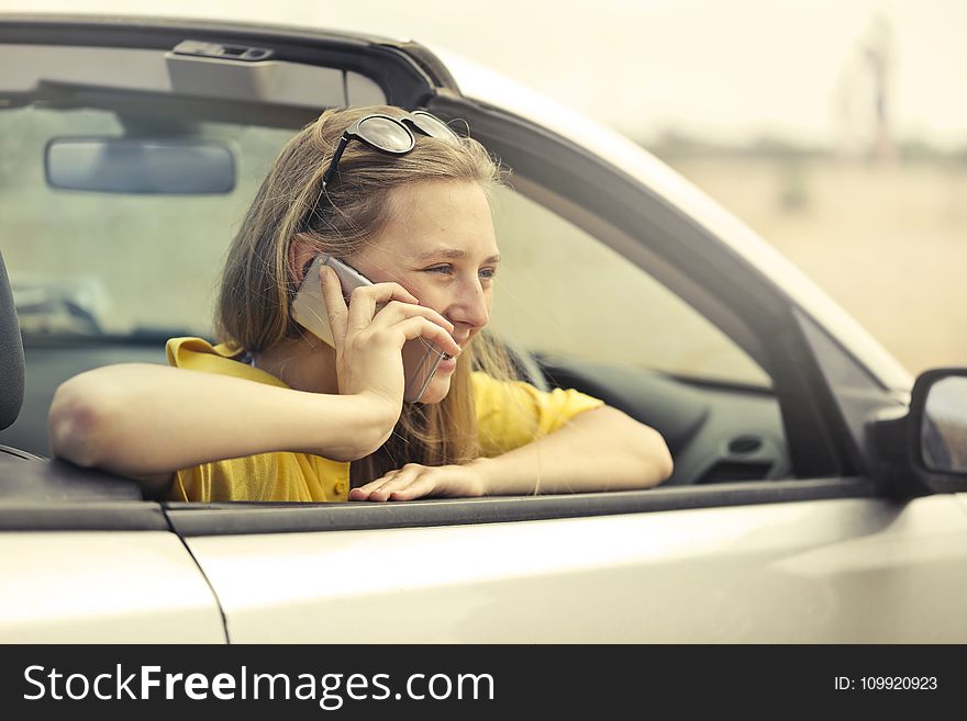 Blonde-haired Woman In Yellow T-shirt Wearing Black Sunglasses Holding Silver Smartphone