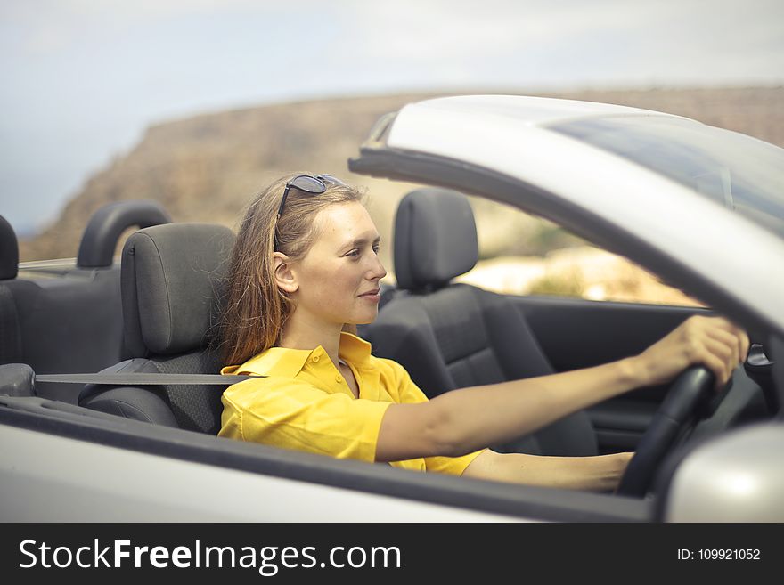 Woman in Yellow Shirt Driving a Silver Car