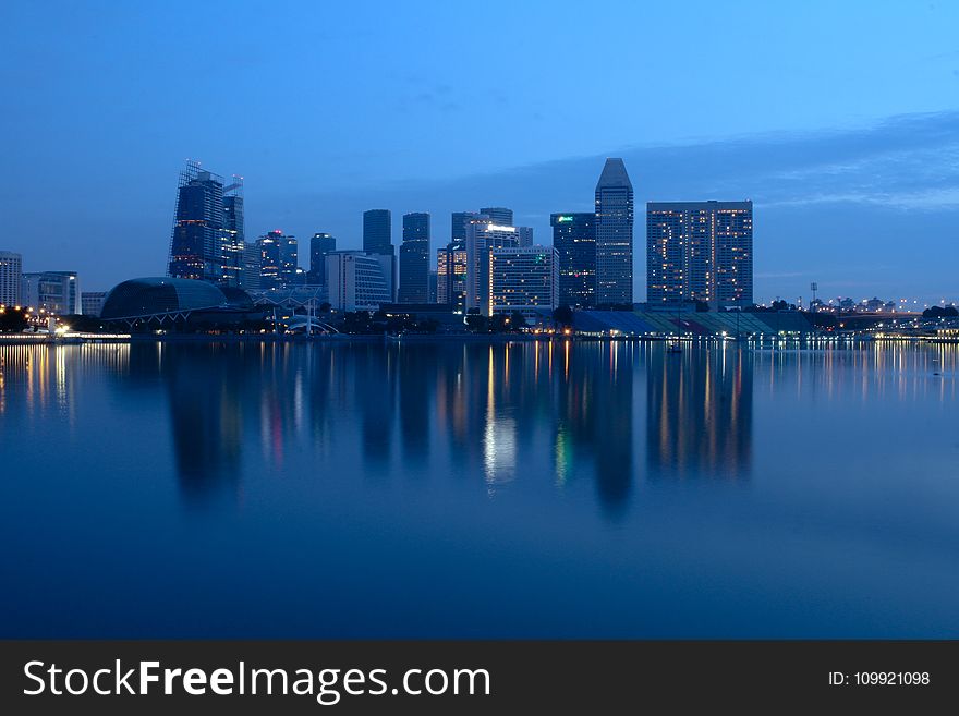 City Buildings Beside Body Of Water During Night Time