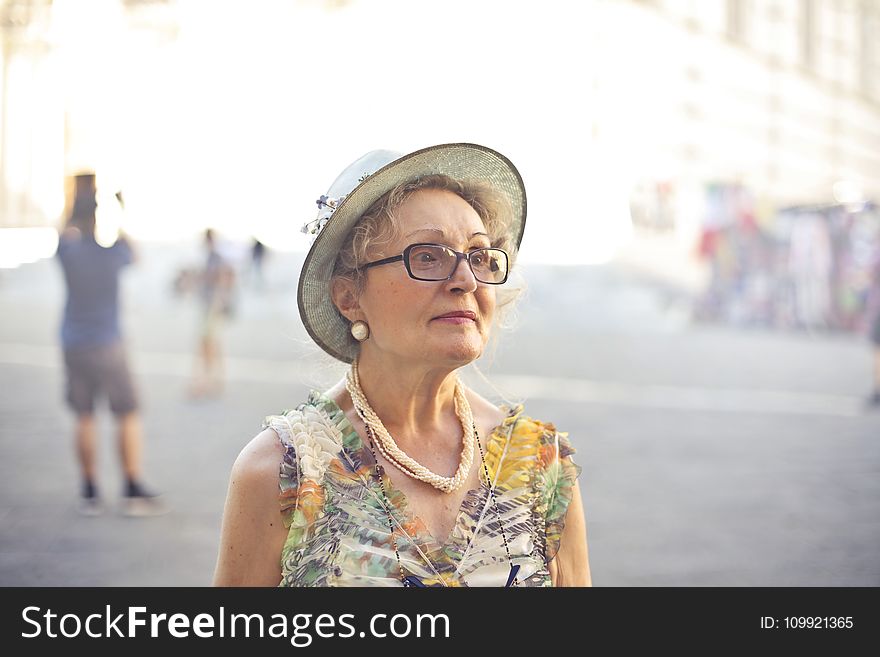 Depth of Field Photography of Woman in Pastel Color Sleeveless Shirt and White Sunhat