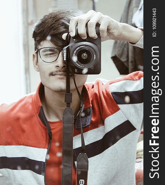 Man in Red and White Full-zip Jacket Holding Canon Dslr Camera