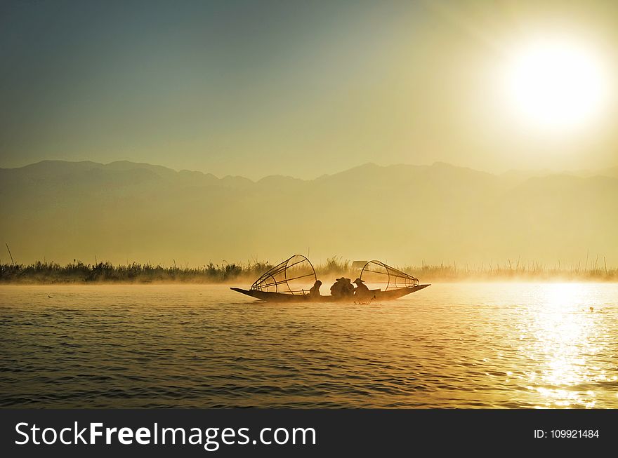 Group Of People Riding Boat In The Middle Of Water During Sunrise