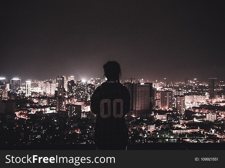 Photo Of A Person Watching Over City Lights During Night Time