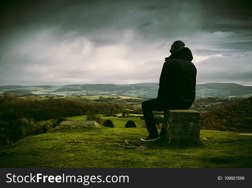 Man in Black Jacket Sitting on Block