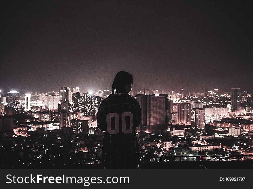 Photo of a Person Watching over City Lights during Night Time