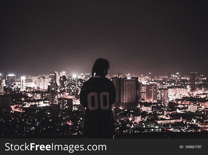 Photo Of A Person Watching Over City Lights During Night Time