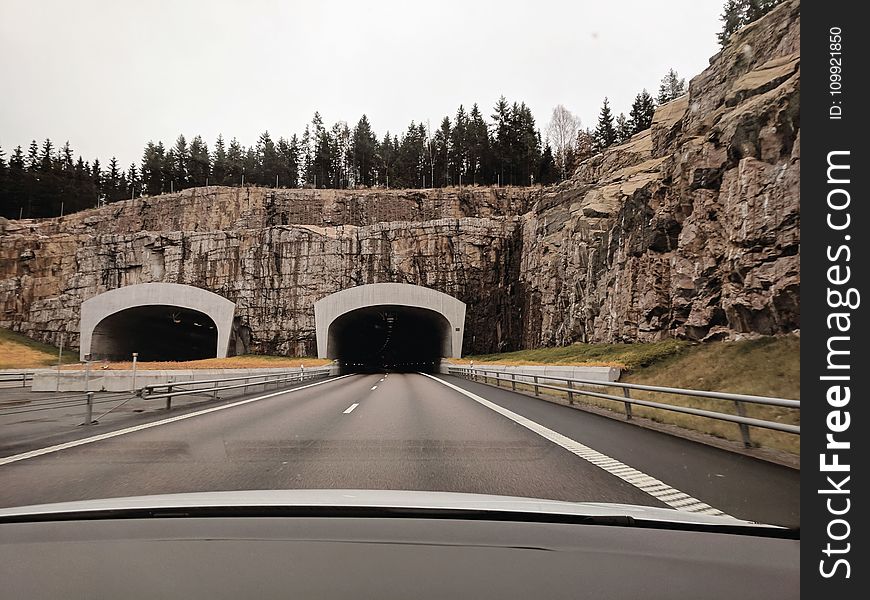 Photo of Two Highway Tunnels in Cliff Under Cloudy Sky