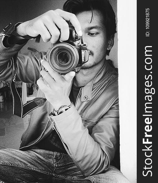 Monochrome Photography of Man Holding Black Nikon Camera