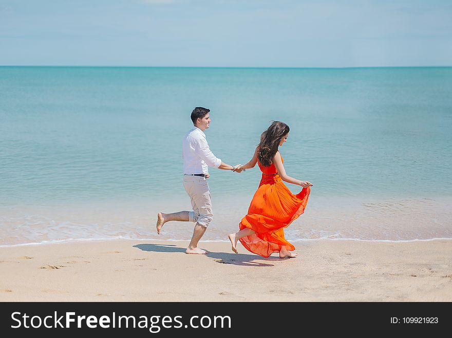 Man and Woman Walks Beside Green Sea