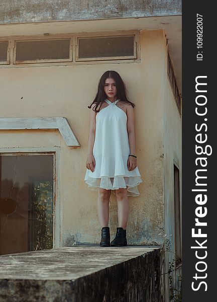 Woman In White Dress Standing On Concrete Wall