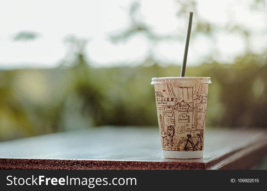 Selective Focus Photo of White Plastic Cup With Lid and Straw