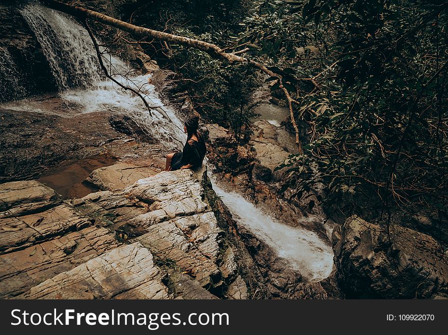 Woman Sitting on Edge Beside Flowing River
